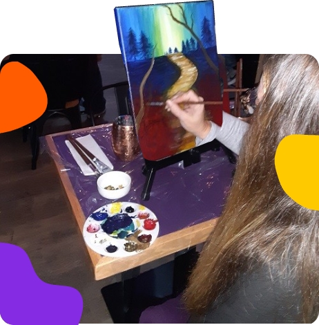 A woman is painting on an easel at a restaurant.