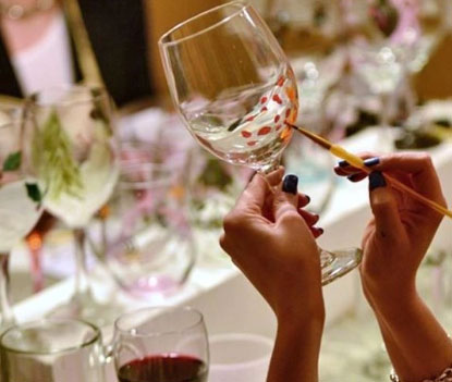A close-up of a woman painting a wine glass.