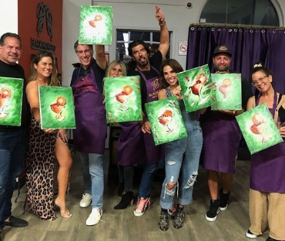 A group of people in aprons holding up paintings.