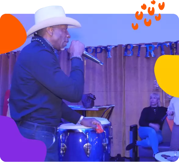 A man in a cowboy hat singing at a birthday party.