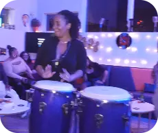 A woman is playing a conga drum in a bar.