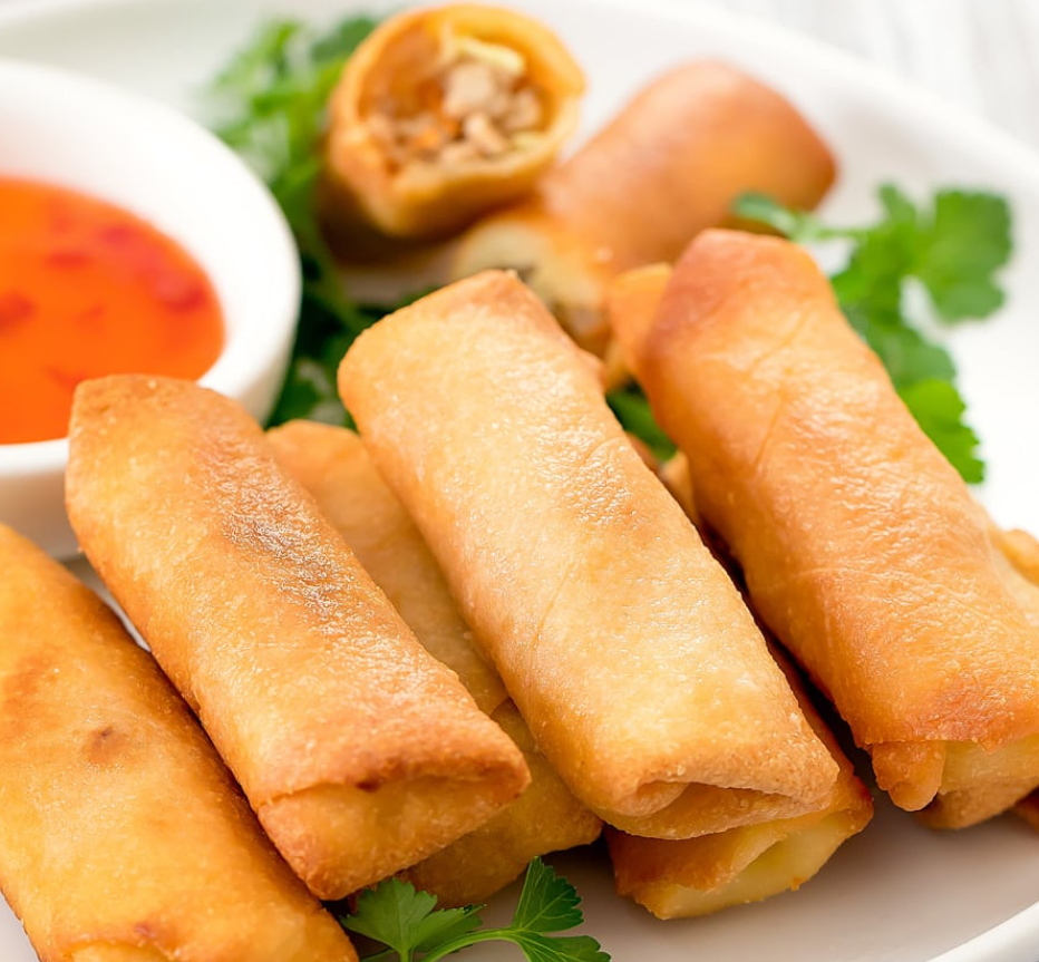 Vietnamese spring rolls on a plate with dipping sauce.