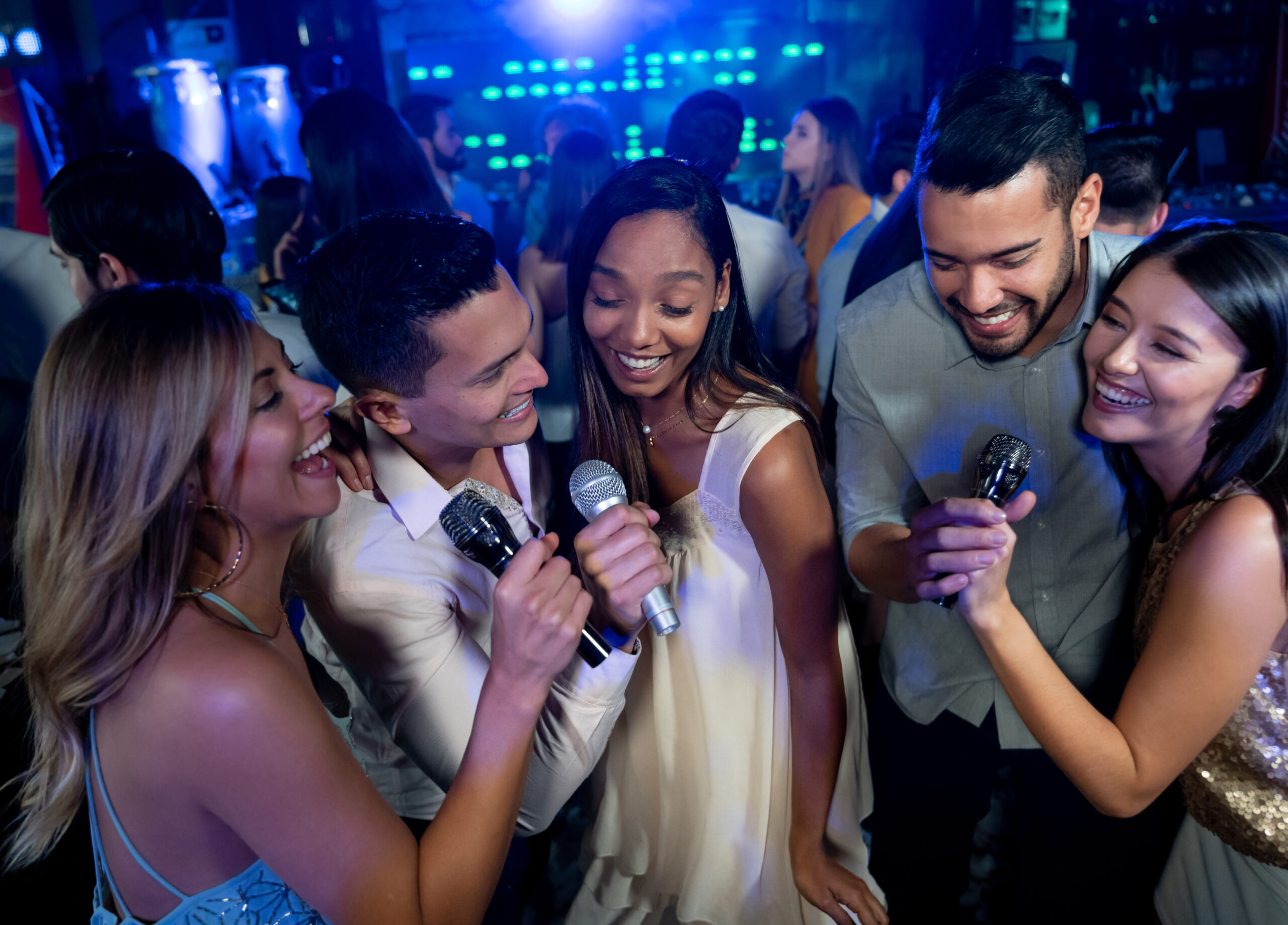 A group of people singing at a party with microphones.