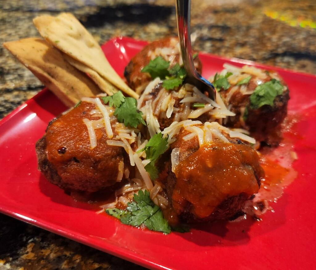 Mexican meatballs on a red plate with a fork.