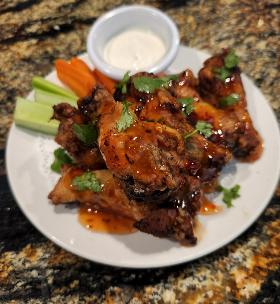 Chicken wings on a plate with carrots and celery.
