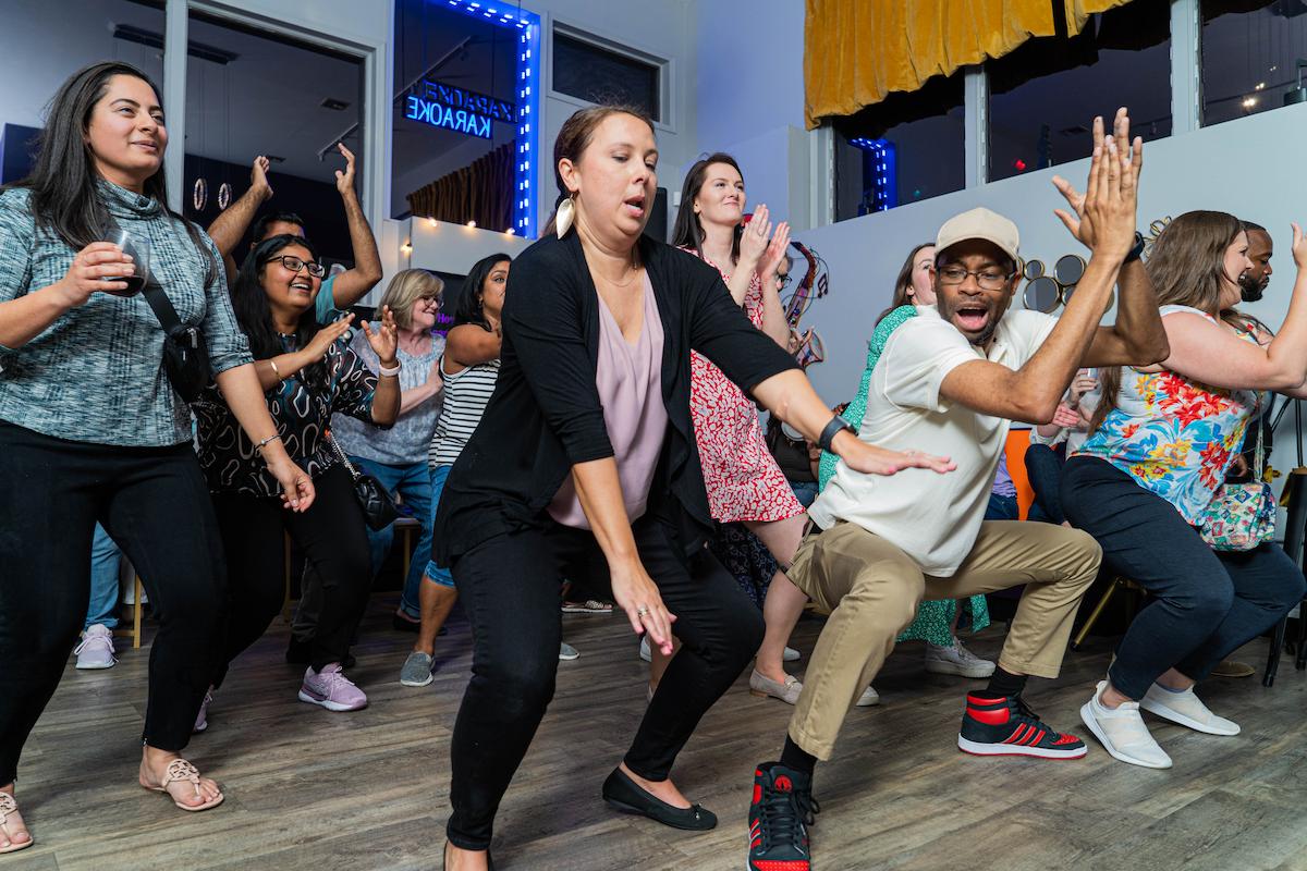 Coworkers singing karaoke together during a Nyack team-building event at Black Parakeetz